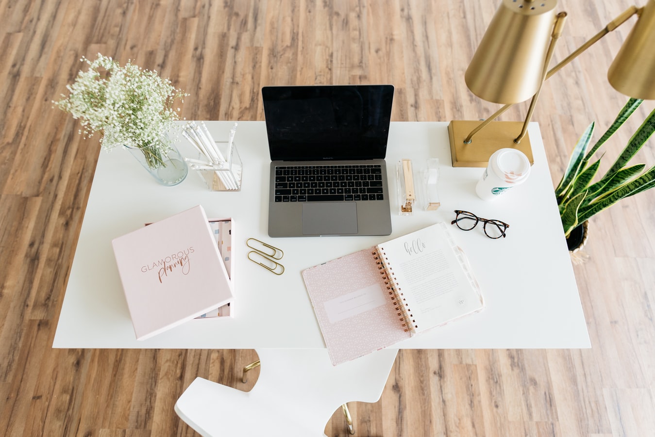 brightly lit office with desk, flowers and plant