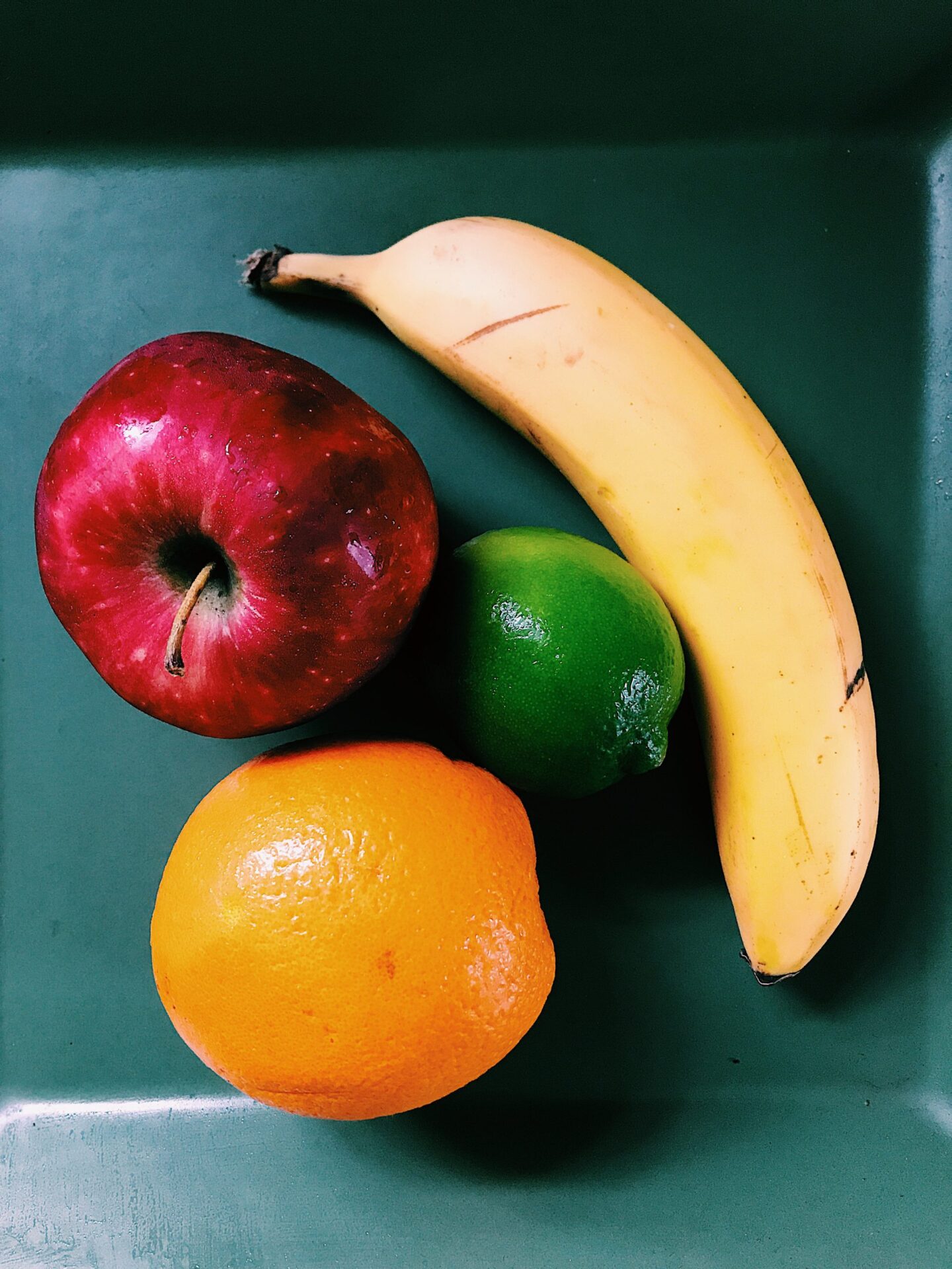 banana, apple, lime and orange displayed on plate