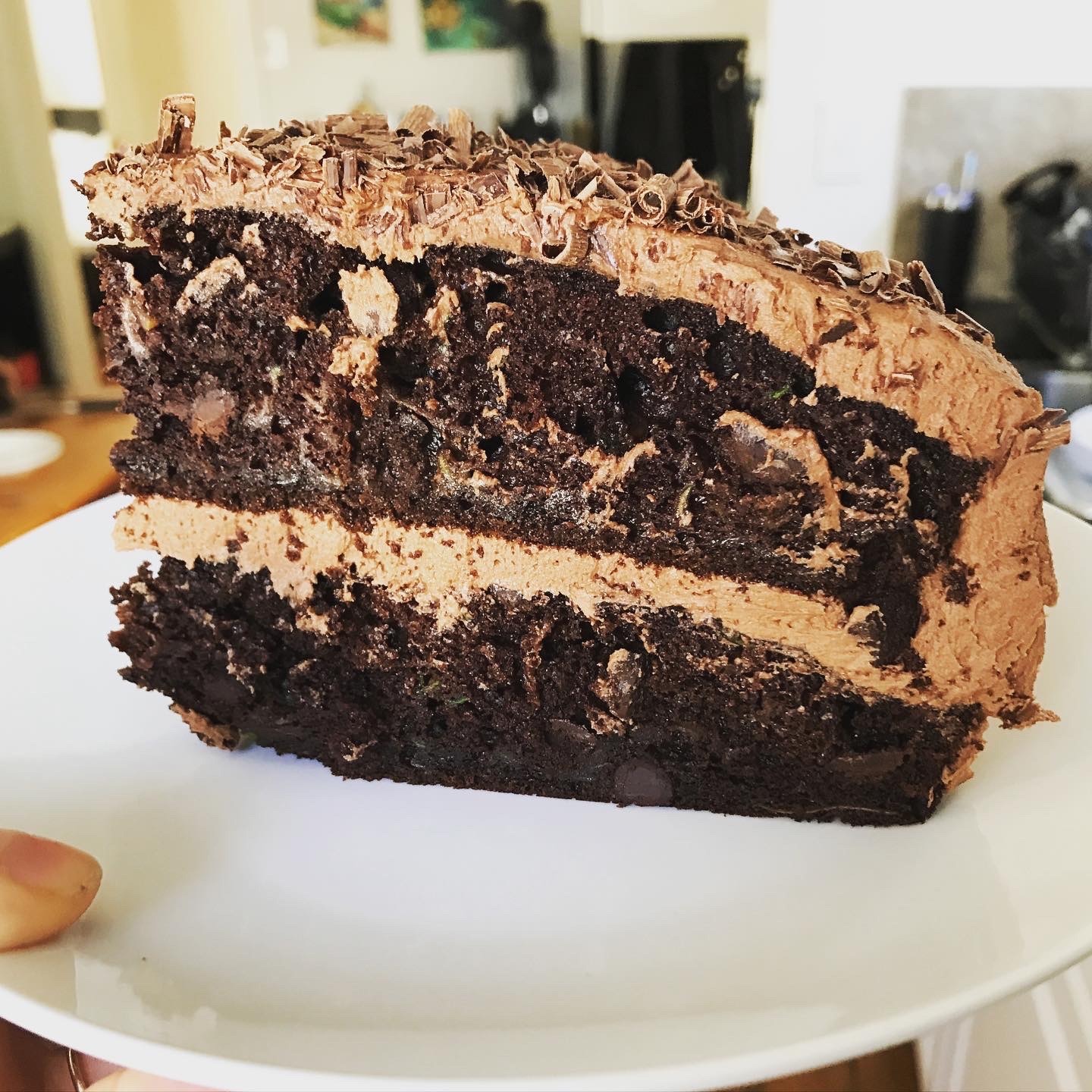 slice of dark chocolate zucchini cake with chocolate shavings and frosting