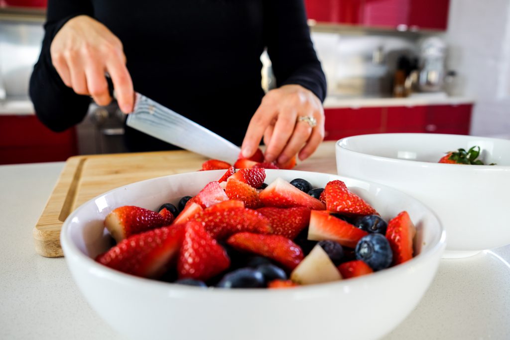 woman registered dietitian nutritionist slicing strawberries to put into bowl of fresh berries