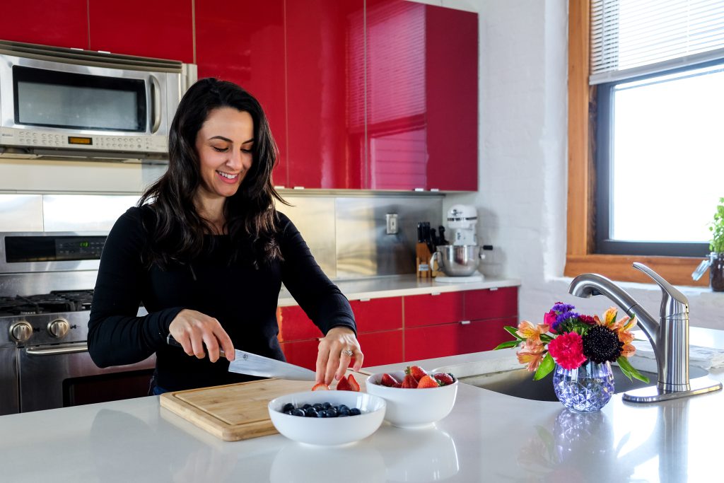 Woman slicing strawberries in a bright kitchen with red cabinets